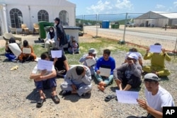 This image provided by Muhammad Arif Sarwari, shows Afghans who fled the Taliban takeover of their country staging a protest at Camp Bondsteel in Kosovo, June 1, 2022.