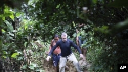 Jurnalis Inggris Dom Phillips (kanan) dan seorang pria suku Yanomami, berjalan di desa Maloca Papiu, negara bagian Roraima, Brazil, November 2019. Phillips dilaporkan hilang di bagian terpencil wilayah Amazon Brazil, Senin, 6 Juni 2022. (AP Photo/Joao Laet)