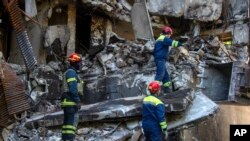 Ukrainian emergency service personnel work outside a damaged building following shelling, in Kharkiv, Ukraine, Saturday, June 4, 2022.