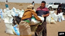 FILE - Yemeni families receive flour rations and other basic food supplies from charities in the province of Lahj, in southern Yemen, March 29, 2022. 