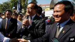 Opposition leader of Cambodia National Rescue Party Sam Rainsy, center, delivers a speech next to his Deputy President Kem Sokha, right, during a gathering to mark Human Rights Day, in front of National Assembly, in Phnom Penh, Cambodia, Wednesday, Dec. 10, 2014. (AP Photo/Heng Sinith)
