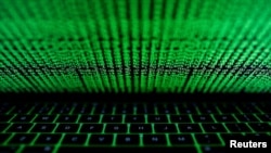 FILE - This photo illustration shows a computer keyboard lit by displayed cyber code.