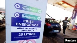 A placard reading "Energy crisis. Maximum limit 25 litres per filling" is seen as a man fills up a car during a fuel strike, at a gas station near Lisbon, Portugal, Aug. 12, 2019.