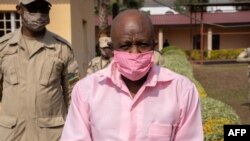 Le héros de "Hotel Rwanda" Paul Rusesabagina (à droite) dans l'uniforme rose des détenus de la prison de Nyarugenge avec des agents du Service correctionnel du Rwanda (RCS) se rend à la Cour de justice de Nyarugenge à Kigali, Rwanda, le 25 septembre 2020. (Simon Wohlfahrt / AFP)