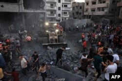 Sebuah buldoser membersihkan puing-puing ketika orang-orang berkumpul di sebuah lingkungan di Rafah di Jalur Gaza selatan setelah terkena serangan Israel pada 15 Oktober 2023. (Foto: AFP)