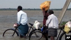 Sri Lankan men push their bicycles through flood waters after heavy rains in Batticaloa, about 320 km (199 miles) east of Colombo, 13 Jan 2011