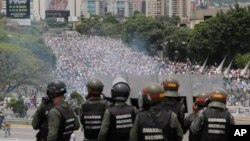 In this May 3, 2017 photo, Bolivarian National Guards stand on a highway overlooking an anti-government march trying to make its way to the National Assembly in Caracas, Venezuela.