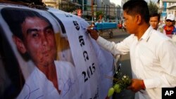A Cambodian worker gives a signature on a poster of Chea Vichea during the 11th anniversary of assassination of Chea Vichea, former head of Cambodia's Free Trade Union of Workers, in Phnom Penh, Cambodia, Thursday, Jan. 22, 2015. (AP Photo/Heng Sinith)
