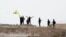 Fighters with the Kurdish People's Protection Units, or YPG, wave their yellow triangular flag on the outskirts of Tal Abyad, Syria, June 15, 2015.