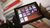 A woman holds up an iPad with the iTunes U app after a news conference introducing a digital textbook service, in New York, January 2012. (file photo)