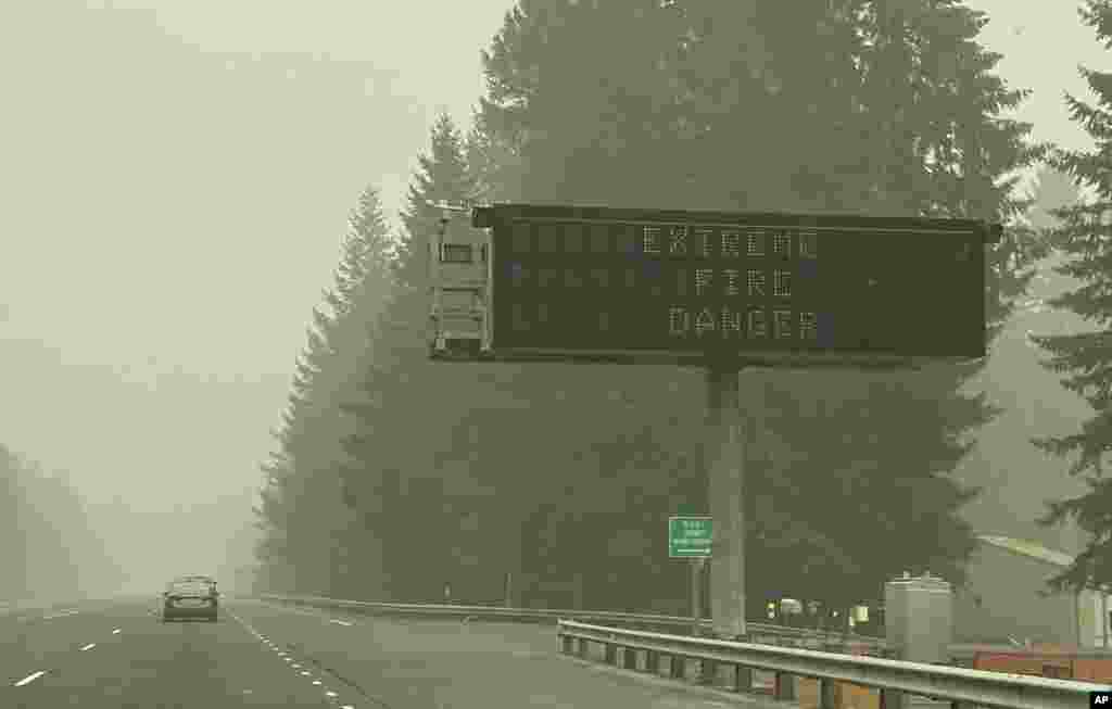 ផ្លាកសញ្ញាបង្ហាញអំពីគ្រោះថ្នាក់នៃភ្លើងឆេះព្រៃ ត្រូវបានដាក់នៅលើផ្លូវជាតិមួយ នៅទីក្រុង Sandy ដែលគ្របដណ្តប់ដោយផ្សែង ក្នុងរដ្ឋ Oregon កាលពីថ្ងៃទី ១៤ ខែកញ្ញា ឆ្នាំ ២០២០។ 