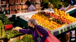 FILE - A shopper wearing a protective mask as a precaution against the spread of the coronavirus selects produce at the Reading Terminal Market in Philadelphia, Friday, April 22, 2022. (AP Photo/Matt Rourke)