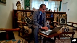 Louis Clemis, a church youth leader, reviews photos of the church during an interview with The Associated Press in Baghdad, Iraq, Feb. 17, 2021. He was attending Mass in October 2010 when dozens were killed in the massacre that changed his life forever.