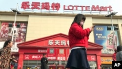 អ្នក​ស្រុក​ដើរ​កាត់​ហាង Lotte Mart កន្លែង​ដែល​វិធានការ​សន្តិសុខ​បន្ថែម​ត្រូវ​បាន​គេ​ដាក់​នៅ​ក្នុង​ក្រុង​ប៉េកាំង ប្រទេស​ចិន កាលពី​ថ្ងៃទី១៧ ខែមីនា ឆ្នាំ២០១៧។