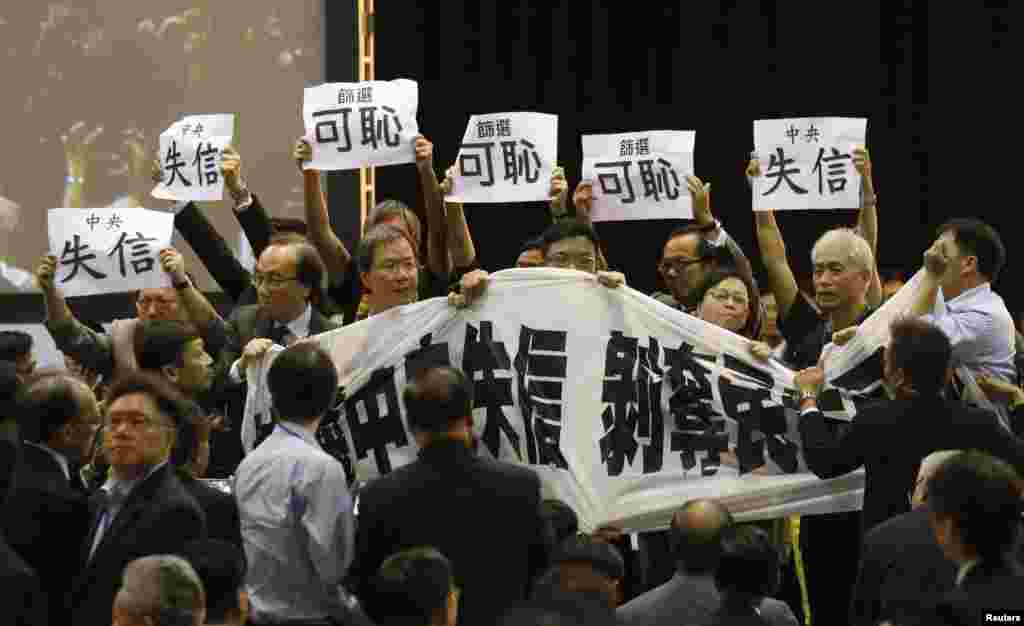 Pro-democracy lawmakers hold up a banner and placards to protest as Li Fei speaks during a briefing session in Hong Kong, Sept. 1, 2014.