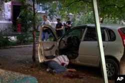A dead body of a man killed by the Russian shelling lies by his car in city center in Slavyansk, Donetsk region, Ukraine, Monday, June 27, 2022. (AP Photo/Efrem Lukatsky)