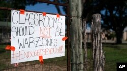 A sign asking for a change hangs on a fence near Robb Elementary School in Uvalde, Texas, Friday, June 3, 2022. (AP Photo/Jae C. Hong)