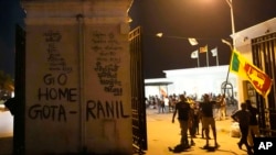 Protesters walk past a vandalized security gate at the entrance to president's official residence in Colombo, Sri Lanka, July 9, 2022.