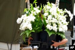 A worker brings condolence flowers to the residence of Japan's former Prime Minister Shinzo Abe, who was assassinated July 9, 2022, in Tokyo.