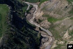 Receding floodwaters flow past sections of North Entrance Road washed away at Yellowstone National Park in Gardiner, Mont., June 16, 2022.