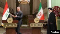 Iranian President Ebrahim Raisi and Iraqi Prime Minister Mustafa al-Kadhimi arrive for a news conference in Tehran, Iran, June 26, 2022. (President Website/West Asia News Agency/Handout via Reuters)