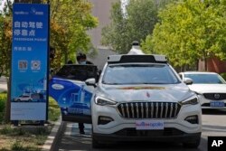 Seorang pria mengenakan masker masuk ke Baidu Apollo Robotaxi di tempat penjemputan penumpang di Taman Shougang, Beijing, Minggu, 2 Mei 2021. (AP/Andy Wong)
