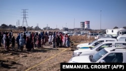 Les résidents du quartier informel de Nomzamo réagissent à une scène de crime où 14 personnes ont été abattues dans une taverne de Soweto le 10 juillet 2022.