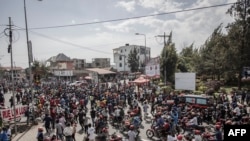 Des habitants se rassemblent au passage du convoi transportant le corps d'un militaire de la République démocratique du Congo depuis le poste frontière rwandais de Rubavu (Gisenyi) le 17 juin 2022.