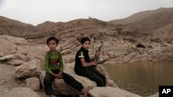 FILE - A 17 year-old boy holds his weapon at the High dam in Marib, Yemen, July 30, 2018. 
