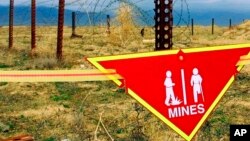 FILE - Tanda peringatan internasional tentang ranjau tergantung di dekat ladang ranjau di Pangkalan Udara Bagram, 22 Maret 2002. (Mikhail Metzel/AP)