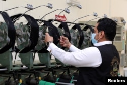 Seorang pekerja Saudi mengenakan masker saat mempersiapkan Kiswah, kain sutra yang menutupi Ka'bah, menjelang haji tahunan, di sebuah pabrik di kota suci Mekah, Arab Saudi 15 Juli 2021. (REUTERS/Ahmed Yosri)