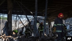 Ukrainian State Emergency Service firefighters work to take away debris at a shopping center burned after a rocket attack in Kremenchuk, Ukraine, June 28, 2022.