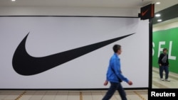 FILE - People walk past a closed store of the sporting goods retailer Nike at a shopping mall in Saint Petersburg, Russia, May 25, 2022. 