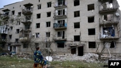 A woman sits in front of her building, which has been partialy destroyed after a Russian missile hit on a four-storey residential building in Chasiv Yar, Bakhmut District, eastern Ukraine, on July 10, 2022.