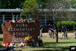 FILE - Investigators search for evidence outside Robb Elementary School in Uvalde, Texas, May 25, 2022, after an 18-year-old gunman killed 19 students and two teachers.