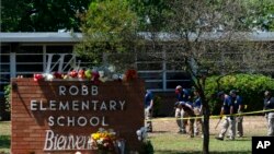 FILE - Investigators search for evidence outside Robb Elementary School in Uvalde, Texas, May 25, 2022, after an 18-year-old gunman killed 19 students and two teachers.