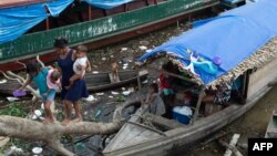 Members of an Indigenous family who temporarily lives on a boat while staying in the city, walk on a tree branch to reach the ground in Atalaia do Norte, state of Amazonas, Brazil, on June 22, 2022. 