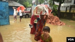 Members of a flood-affected family leave their home in the Gowainghat subdistrict of Sylhet district, Bangladesh, and head toward a flood shelter. (Md Serajul Islam/VOA)