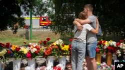 People lay flowers to pay last respects to victims of the Russian rocket attack at a shopping center in Kremenchuk, Ukraine, June 29, 2022. 