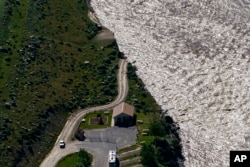 FILE - A road ends where floodwaters washed away a house in Gardiner, Mont., on June 16, 2022.