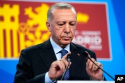 FILE - Turkish President Recep Tayyip Erdogan tests the microphone prior to addressing a media conference at a NATO summit in Madrid, June 30, 2022.