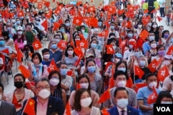 Massa membawa bendera China dan Hong Kong dalam perayaan 25 tahun penyerahan Hong Kong ke China dari Inggris, di Hong Kong, 26 Juni 2022. (REUTERS/Lam Yik)