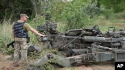 지난 18일 우크라이나군 병사가 도네츠크주 전선에서 미국산 M777 곡사포 앞에 서 있다. (자료사진)