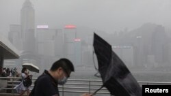 People hold umbrellas in the rain at a waterfront, amid a typhoon warning on the 25th anniversary of the former British colony's handover to Chinese rule, in Hong Kong, China, July 1, 2022.