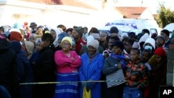 People stand behind a police cordon outside a nightclub in East London, South Africa, June 26, 2022. 