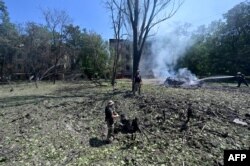 Ukrainian servicemen inspect a hole left after an airstrike in the courtyard of Hotel Industria and civilian residences in the center of Kramatorsk, eastern Ukraine, July 7, 2022.