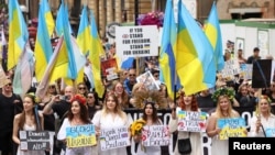 People hold Ukrainian flags and signs in support of Ukraine, as they take part in the 2022 Pride Parade in London, July 2, 2022.