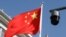 FILE - A surveillance camera overlooking a street hangs next to a Chinese flag in Beijing, China, Nov. 25, 2021. Street cameras are a primary mode of surveillance in China; more than half of the world's nearly 1 billion surveillance cameras are in China.