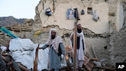 Afghan men sift through debris after an earthquake, in Gayan village, Paktika province, Afghanistan, June 23, 2022.