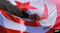 Lors d'une manifestation d'Ennahdha à Tunis, un homme place une copie de la constitution tunisienne sur le drapeau national.